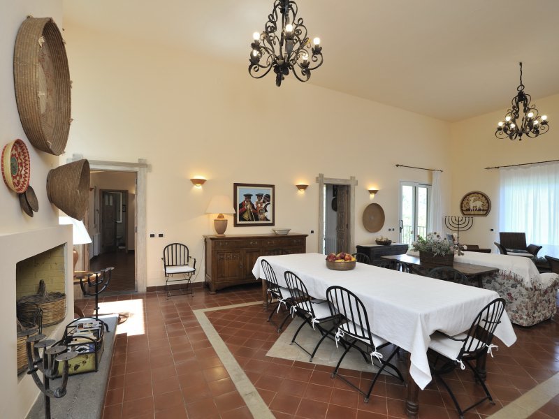 Sardisch eingerichtetes Wohnzimmer mit großem Esstisch und Kamin
