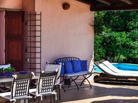 Überdachte Terrasse mit Esstisch aus Granit und Blick zum Pool