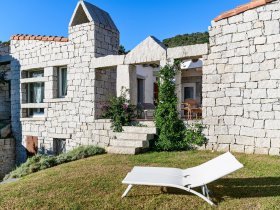 Hausansicht mit Garten mit Sonnenliegen